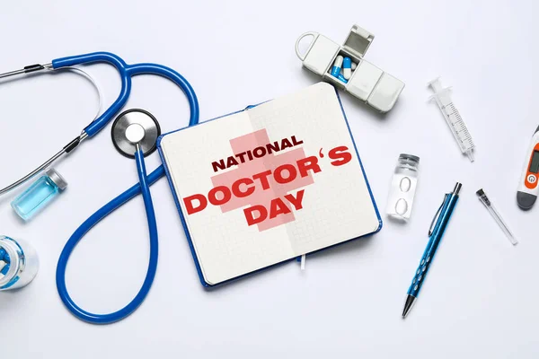 Notebook with text NATIONAL DOCTORS DAY, stethoscope and drugs on light background
