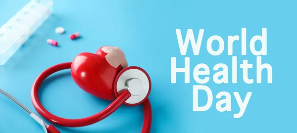 Stethoscope and red heart with medical patch on light blue background. World Health Day