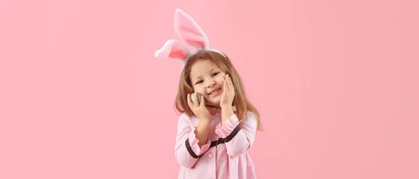有兔子耳朵和粉色背景的复活节彩蛋的小女孩 — 图库照片