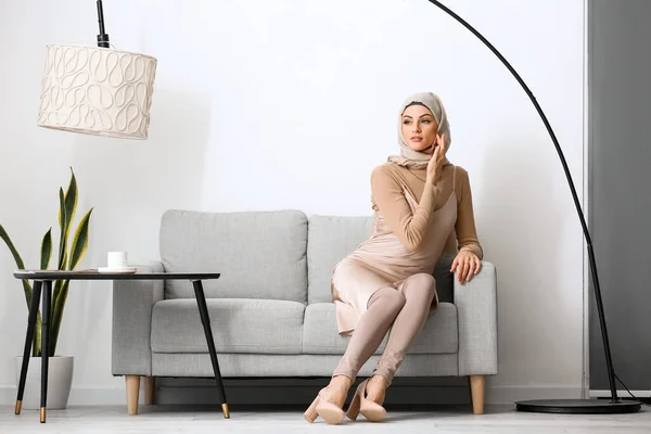 美しいイスラム教徒の女性座っています上のソファに家 — ストック写真