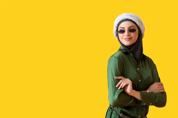 黄色の背景にサングラスでスタイリッシュなイスラム教徒の女性 — ストック写真