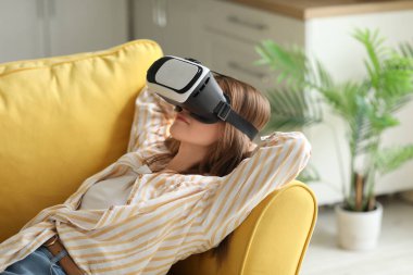 VR gözlüklü güzel bir kadın evdeki kanepede uzanıyor.