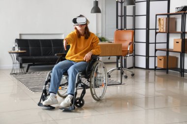 Young woman in wheelchair using VR glasses in office