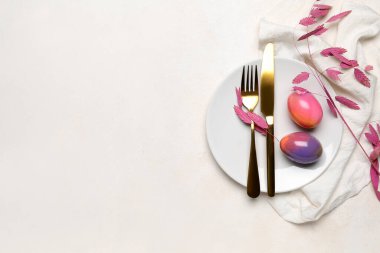 Table setting with Easter eggs, cutlery and plant branch on white background