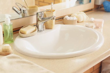 Table with white ceramic sink and bath supplies in room