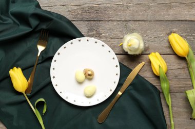 Ahşap zemin üzerinde Paskalya yumurtaları ve laleler olan masa ayarı