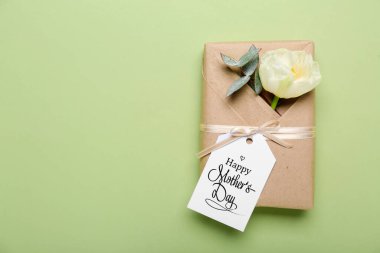 Mesajlı tebrik kartı Mutlu Anneler Günü, hediye kutusu ve yeşil arka planda güzel bir östoma çiçeği