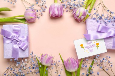 Güzel lale çiçeklerinden yapılmış çerçeve, yazılı tebrik kartı Mutlu Anneler Günü ve pembe arka planda hediye kutuları
