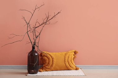 Pembe duvarın yanında ikebana ile dekoratif yastık ve şişe