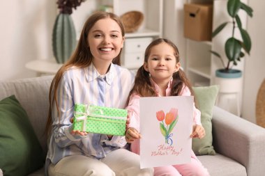 Anneler günü için tebrik kartı olan tatlı küçük bir kız ve annesi evde.