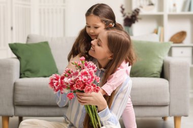 Sevimli küçük kız tatilde annesini çiçeklerle kucaklıyor.