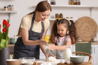 Küçük kız ve annesi Anneler Günü 'nde mutfağa un serpiyorlar.