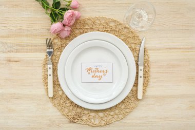 Tahta arka planda gül çiçekleriyle Anneler Günü kutlaması için sofra kurun.