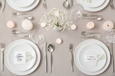 Anneler Günü kutlaması için çingene çiçekleri ve masada yanan mumlarla.