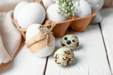 Easter and quail eggs on white wooden background