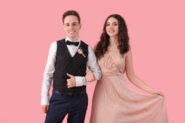Beautiful couple dressed for prom on pink background