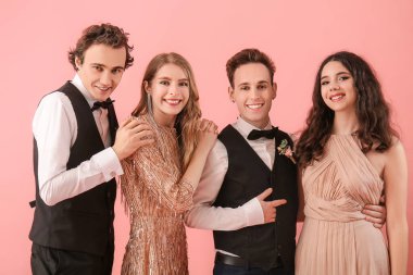 Beautiful couples dressed for prom on pink background
