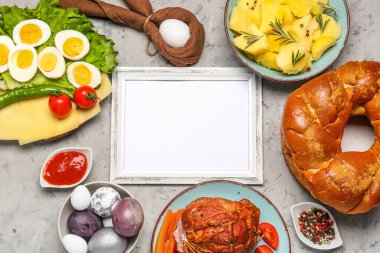 Composition with blank picture frame and tasty dishes for Easter dinner on grunge background