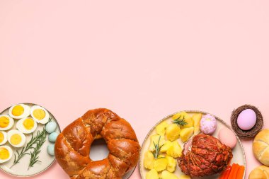 Tasty dishes for Easter dinner on pink background