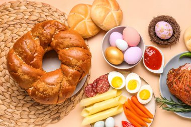 Tasty dishes and painted eggs for Easter dinner on color background