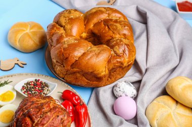 Easter wreath bread and dishes on color background