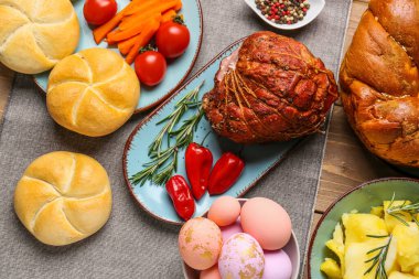 Tasty dishes and painted eggs for Easter dinner on wooden table