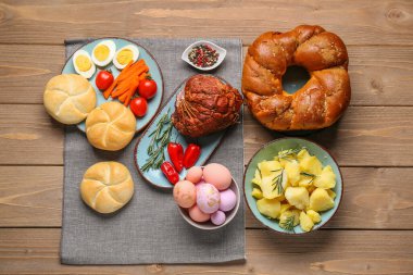 Tasty dishes and painted eggs for Easter dinner on wooden table