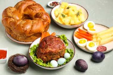 Tasty dishes and beautiful painted eggs for Easter dinner on grunge background