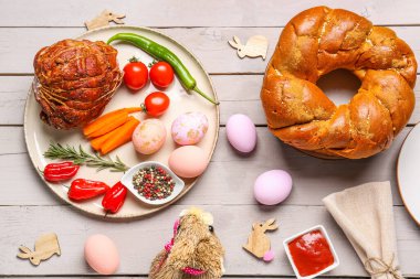 Easter table setting, painted eggs and decor on light wooden background