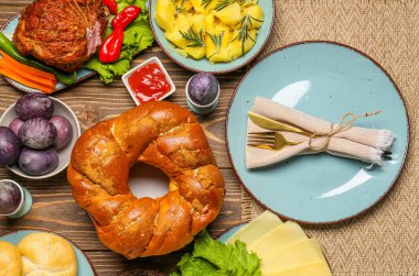 Tasty dishes and painted eggs for Easter dinner on wooden background, closeup