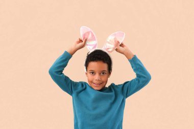 African-American little boy in bunny ears on beige background