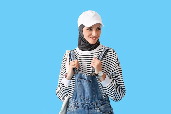 スタイリッシュなイスラム教徒の女性でキャップ付きバッグ上の青の背景 — ストック写真