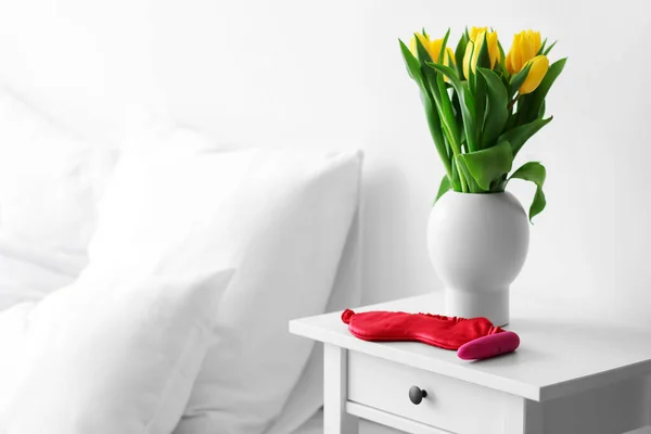 stock image Vibrator, sleeping mask and vase with tulips on table in bedroom