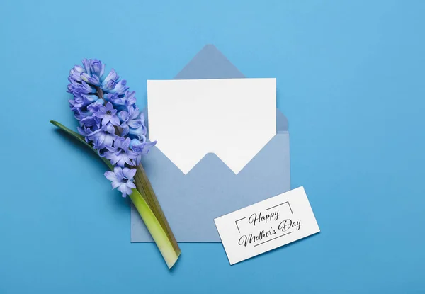 テキスト付きグリーティングカードハッピーマザーズデー 封筒に空白のシートと青の背景に美しいヒヤシンスの花 — ストック写真