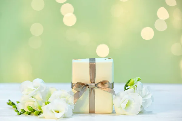 在薄薄的木桌上挂着为母亲节庆祝活动准备的礼物和美丽的自由花 上面点缀着模糊的灯光 — 图库照片