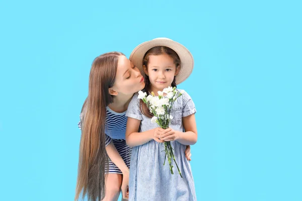 Moeder Zoenen Haar Dochtertje Met Bloemen Blauwe Achtergrond — Stockfoto