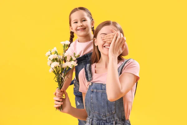 Malá Dívka Zavírající Oči Své Matky Květinami Žlutém Pozadí — Stock fotografie