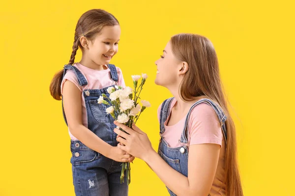Cute Little Girl Greeting Her Mother Flowers Yellow Background — Stock Photo, Image