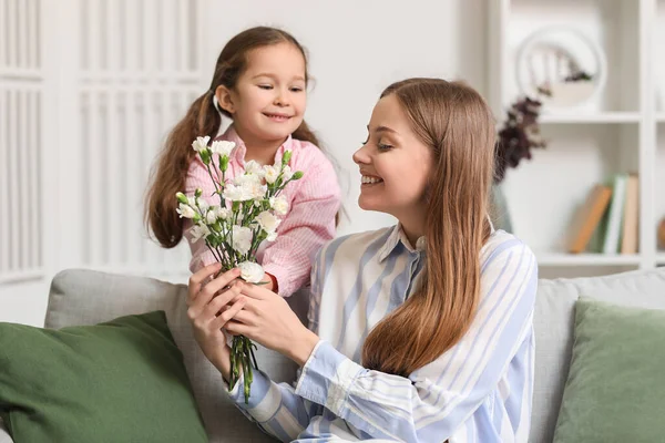 假日时 一个可爱的小女孩带着鲜花在家里问候她的妈妈 — 图库照片