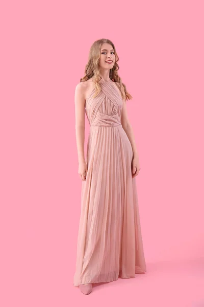 Teenage girl in prom dress on pink background