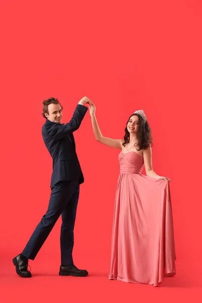 stock image Beautiful couple dressed for prom dancing on red background