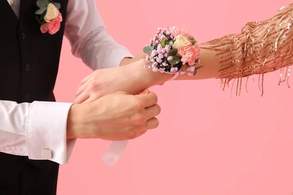 Young Man Tying Corsage His Prom Date Wrist Pink Background — Stock Fotó