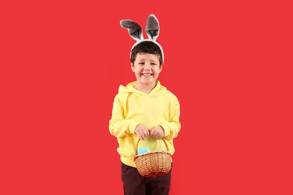Słodki Chłopczyk Króliczymi Uszami Koszykiem Wielkanocnym Czerwonym Tle — Zdjęcie stockowe