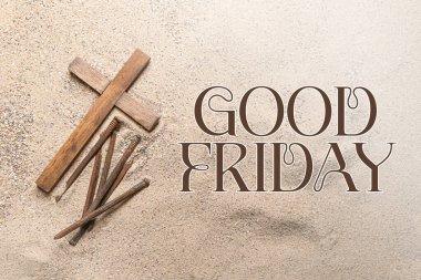 Wooden cross and nails on sand. Good Friday