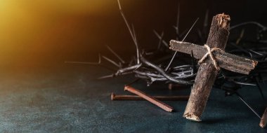 Wooden cross, crown of thorns and nails on dark background with space for text. Good Friday concept