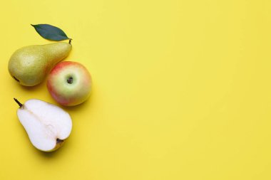 Fresh pears and apple on yellow background