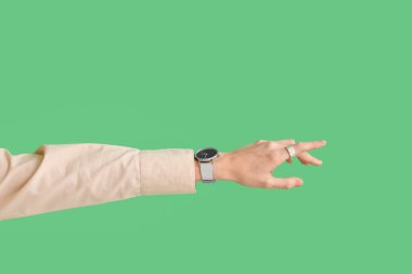 Woman with stylish wristwatch on green background