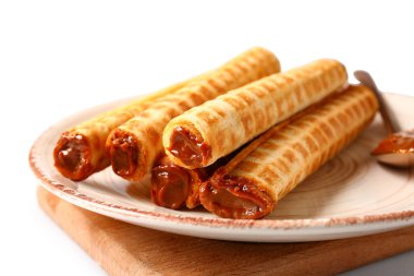 Plate of delicious wafer rolls with boiled condensed milk isolated on white background