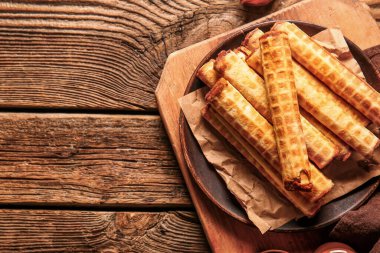 Plate of wafer rolls with boiled condensed milk on brown wooden table