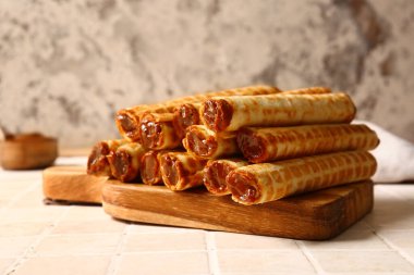 Board of wafer rolls with boiled condensed milk on tile table